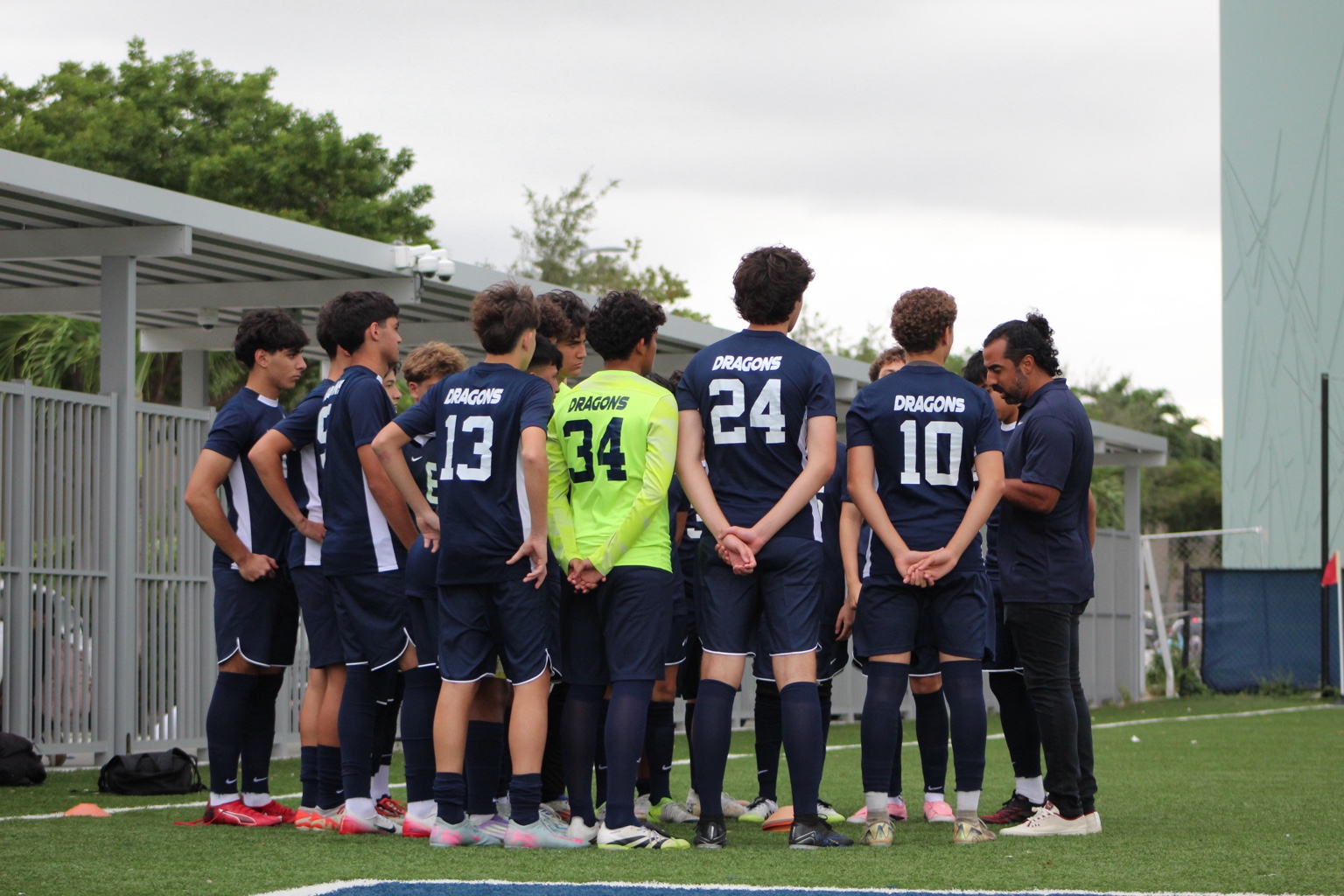 Coach Ricardo Cuenca giving instructions to an older youth soccer team