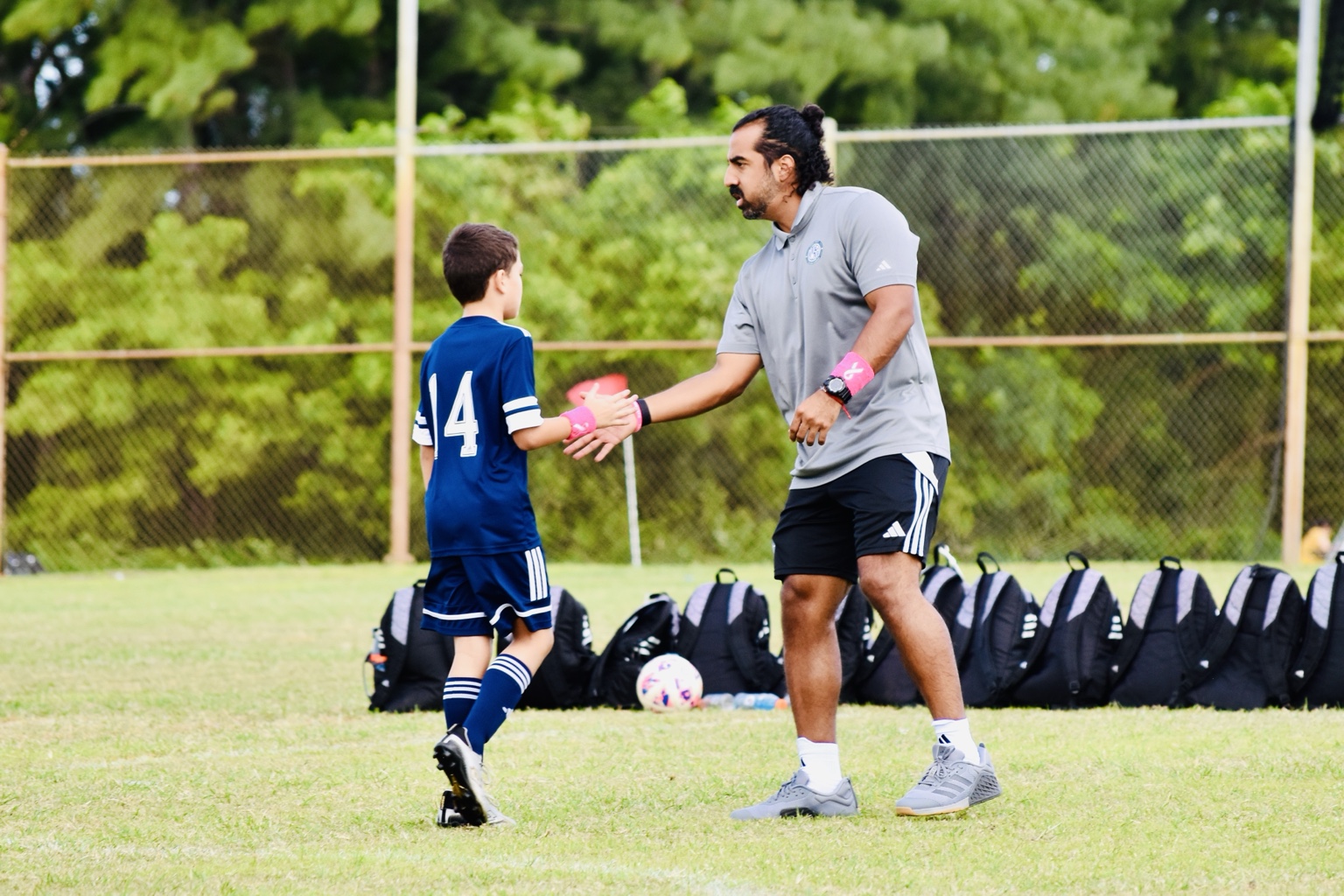 Coach Ricardo Cuenca encouraging a young player after a match